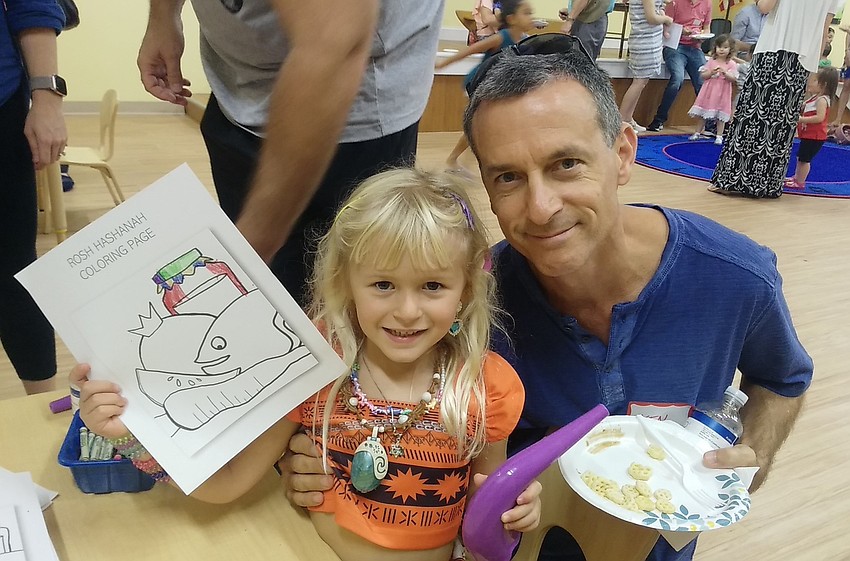 Ken and Josie Beck hold her Rosh Hashanah coloring page and plastic shofar.