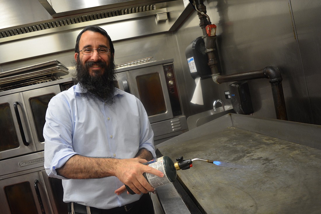 Chabad of Bradenton and Lakewood Ranch Rabbi Mendy Bukiet demonstrates how he will use a blow torch to kosher parts of The Grove&#39;s catering kitchen.
