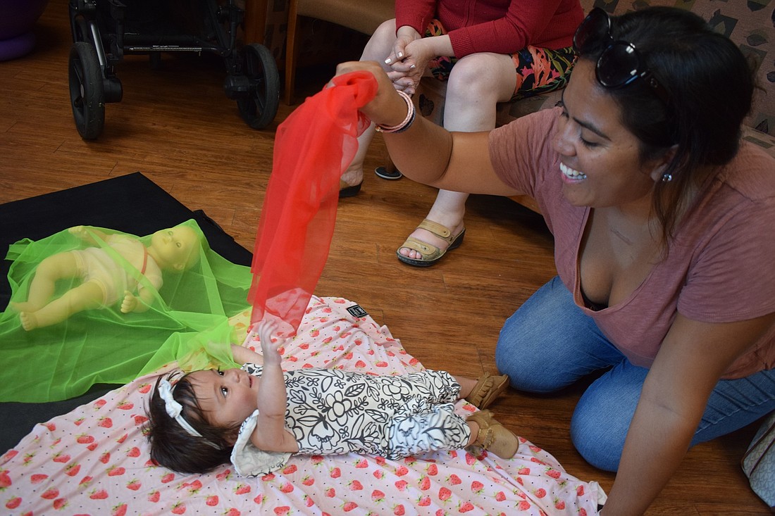 Sarasota resident Denisse Florian, right, and her 4-month-old daughter Camila Zorrilla smile as they play with a scarf during newborn family music class at Lakewood Ranch Medical Center.