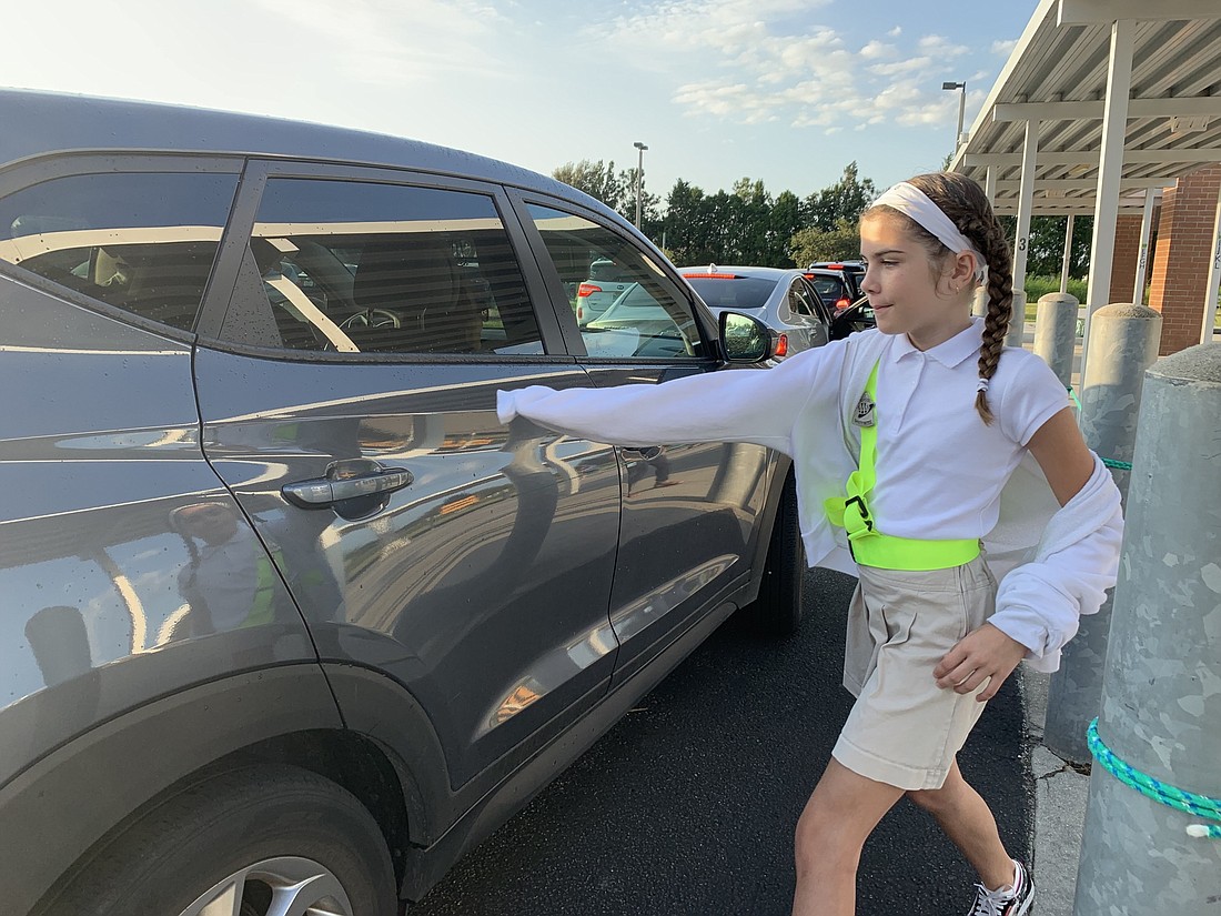 Robert Willis Elementary School fifth-grader and Safety Patrol member Jordyn Milburn goes to open a car door to assist a student as they exit the car to go to school.