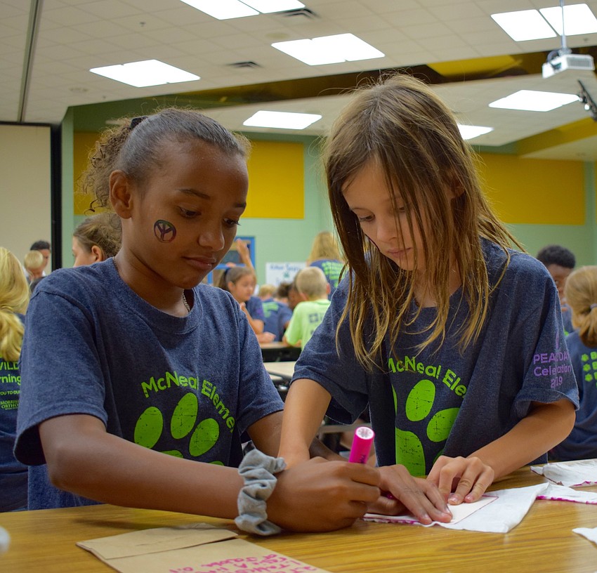 Gilbert W. McNeal Elementary School fourth-graders Raine Thomas, 9, left, and Cora Erhardt, right, work together to cut out pieces of cloth that will be made into eco-friendly food storage.