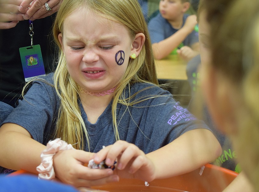 Gilbert W. McNeal Elementary School second-grader Sophie Lowrance makes a face while squishing wet wildflowers and biodegradable paper together to make a seed ball.