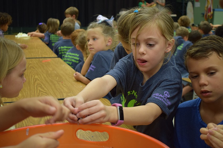 Gilbert W. McNeal Elementary School second-grader Sophia Tabb, 7, center, carefully squishes together wildflowers and biodegradable paper to make a seed ball she can put in her yard at home to help bees.