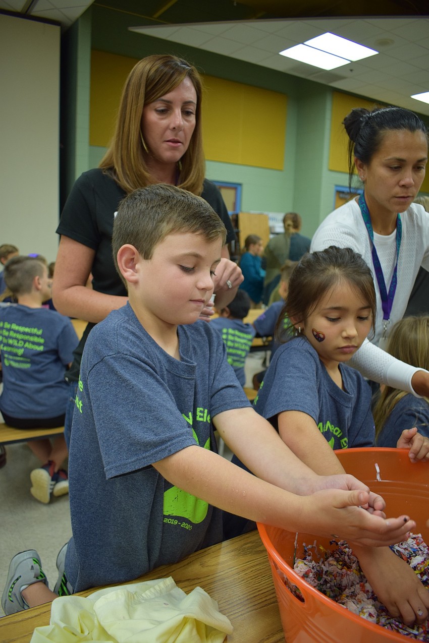 From front left, Gilbert W. McNeal Elementary School second-graders Hayden Laning, 7, and Violet Cadavid, 7, make seed balls with the help of PTO members, from back left, Kelly Laning, who is Hayden's mom, and Jolene Stewart.
