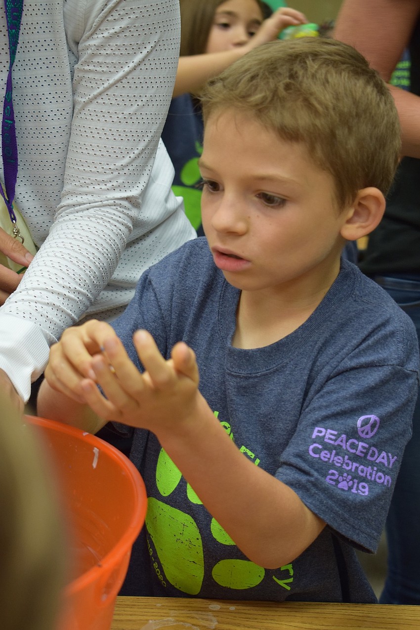 Gilbert W. McNeal Elementary School second-grader Owen Tana, 7, rolls together wildflowers and biodegradable paper to make a seed ball during a bee activity to celebrate International Peace Day.
