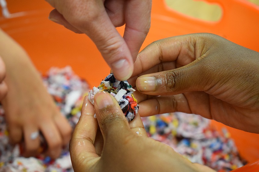 Gilbert W. McNeal Elementary School PTO member Kelly Laning drops seeds into second-grader Haven Wiley's seed ball. The seed balls will grow wildflowers to attract bees so they can continue to pollinate.