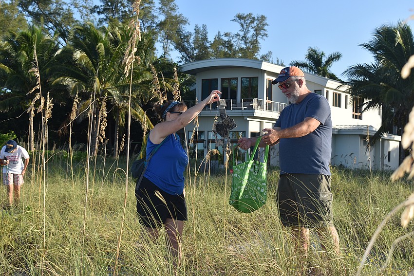 Karey Kaine drops trash into Charles Kaine's bag.
