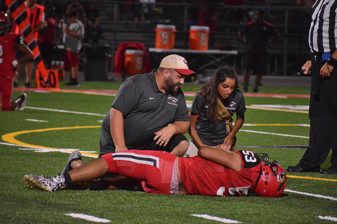 Cardinal Mooney athletic trainer Steven Favia and student trainer Tiffany Thompson give senior Andres Linares assistance.