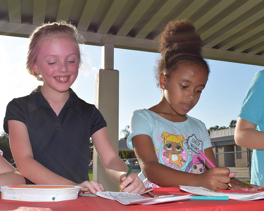 Best friends since kindergarten, second-graders Eliora Ross and Maya Holloway decorate bookmarks together while talking about the Hispanic figures they studied: Jose Feliciano and Cesar Chavez.