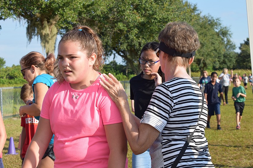 Fifth-grader Jenna Schulman passes volunteer Debbie Greenwald to finish her fifth lap during the walk-a-thon.