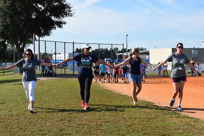 Principal Katherine Price, Student Support Specialist Susie Johnson, Assistant Principal Billie-Jo Fintel and school counselor Phyllis Morales create a chain so students won't pass them on the first lap.