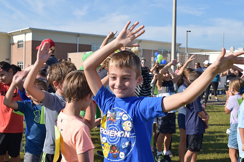 Second-grader Britton Stevens, 7, waves his hands to the music before the second- and third-grade students start the walk-a-thon.