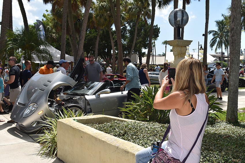 Lynn Tierney takes a photo as others pose in front of the cars.