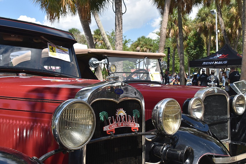 Two cars from the early 20th century shine in the midday sun.