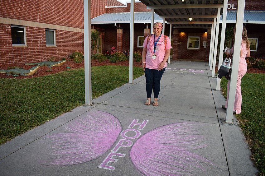 Fourth-grade teacher Sarah Body stands by a chalk drawing that leads to the entrance of B.D. Gullett Elementary School. The PTO drew the messages like 
