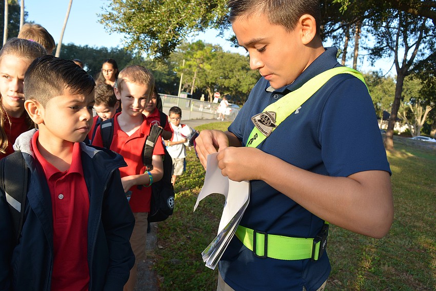 Second-grader Christian Pagan walks around the school from the bus loop and gets a sticker from Safety Patrol member Maddox Hale, 10.