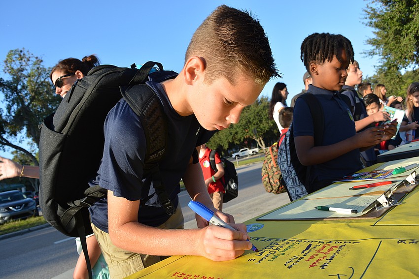 Ten-year-old Jackson Stewart signs in after walking to campus with his family.