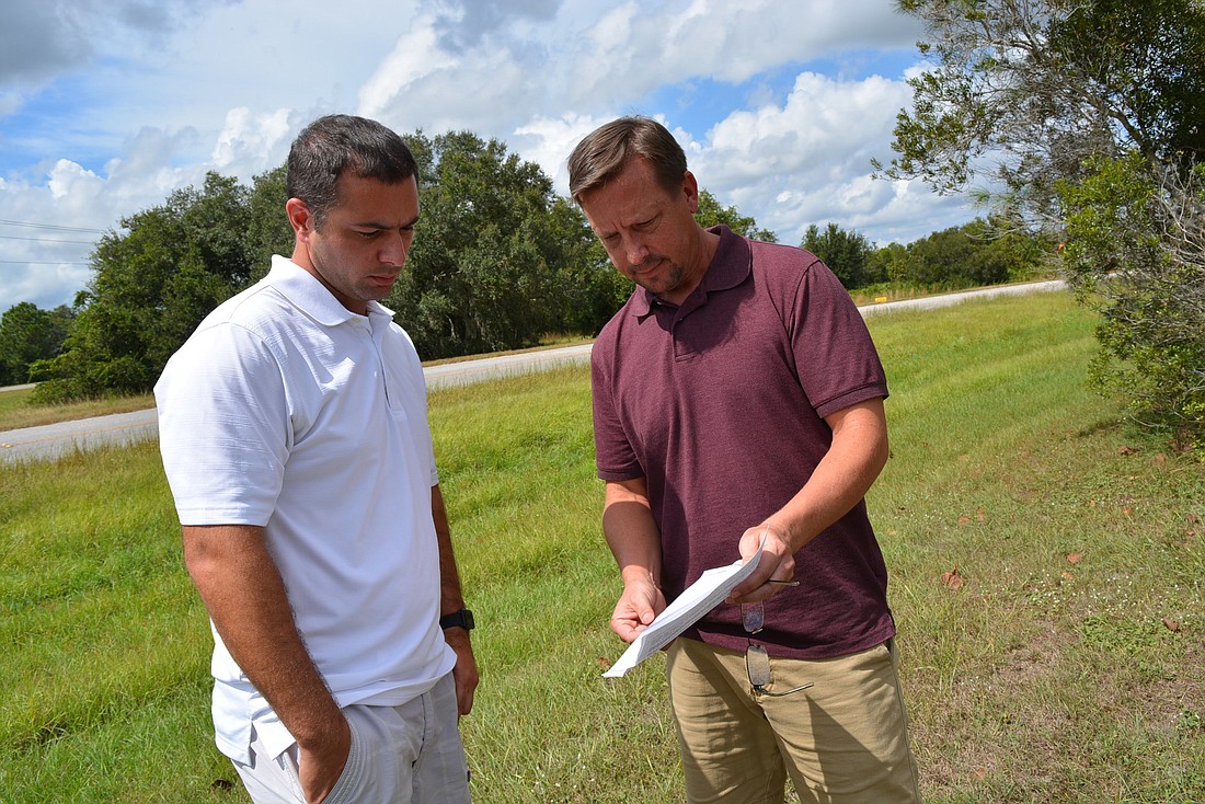Neighbors Danny Chappell and Ron Hunniford look at a map of the site on which Manatee Ranches wants to place a "country store." They say the site, behind them, should not be developed commercially.