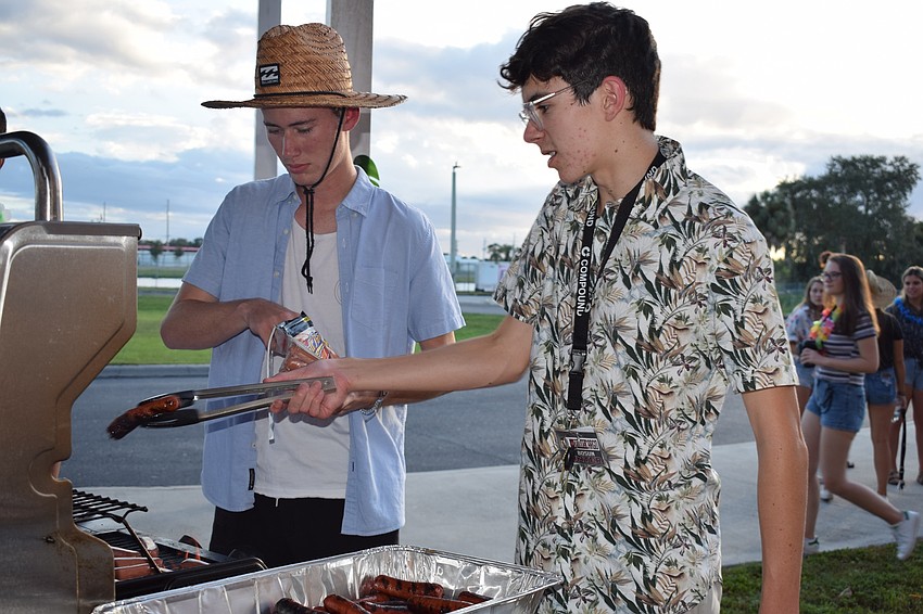 Seniors Jack Soodek and Hunter Gionfriddo grill hotdogs for the annual homecoming bonfire.