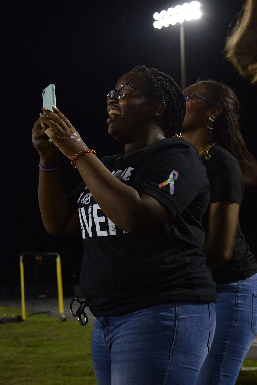 Senior Ludney Guillaume cheers for her friends on the homecoming court as they walk the football field.