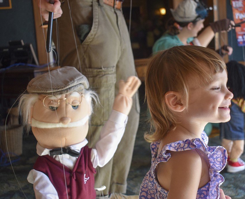 Cora Morgan, 1, smiles after meeting a  marionette.