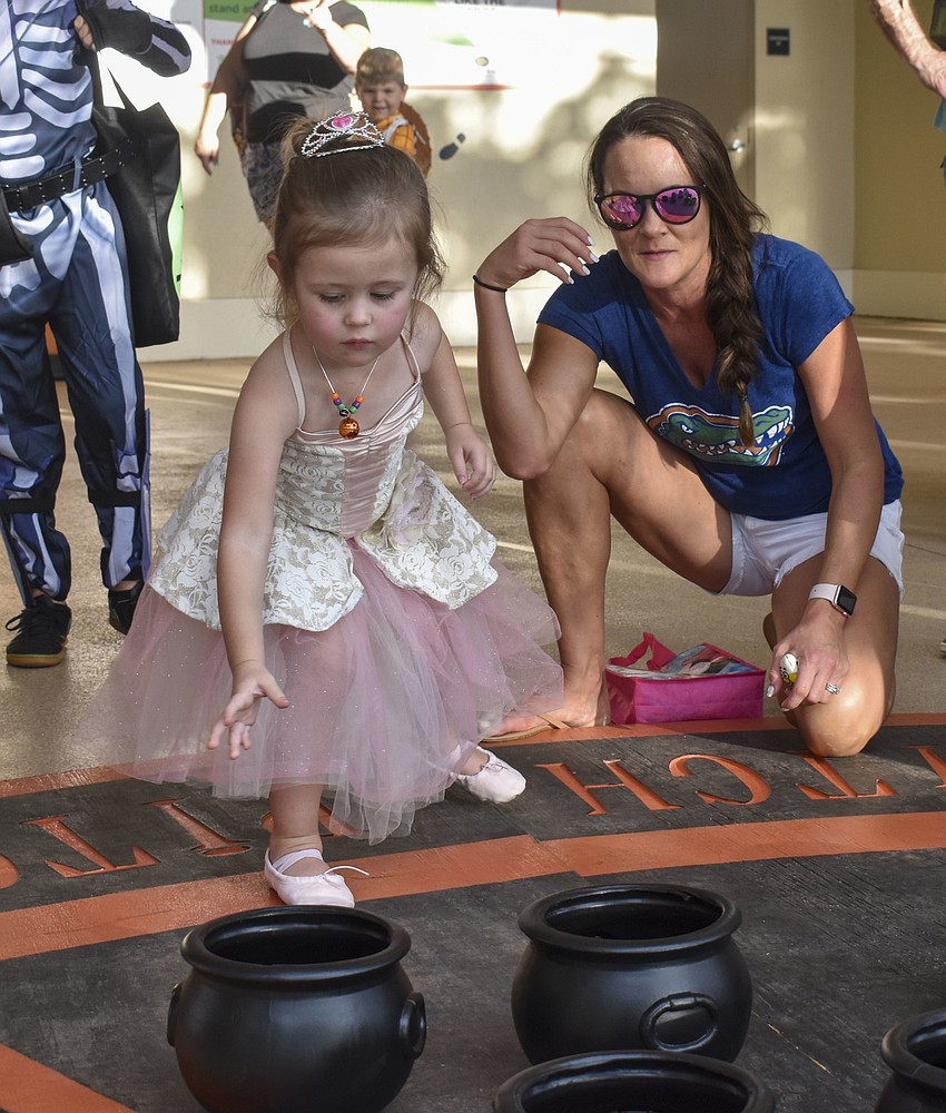 Amelia Brue tosses a candy corn bean bag into a cauldron.