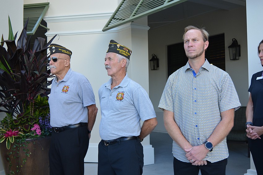 VFW Post 12055 members Gill Ruderman and Charley Busack raised flags with the help of Grand Living's Tim Hutchens, also a veteran.