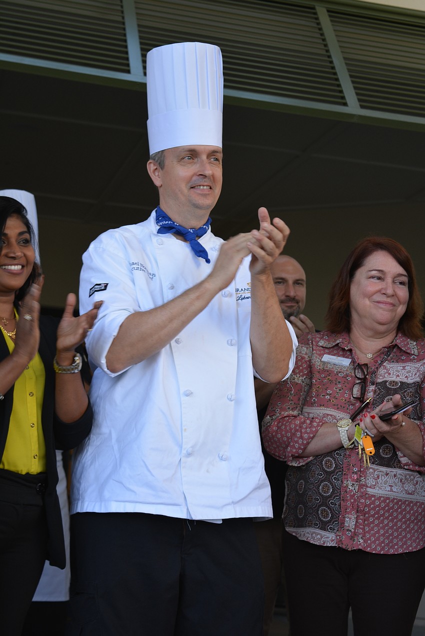 Grand Living at Lakewood Ranch's executive chef Michael Norman claps after a ribbon cutting before heading inside to serve desserts and appetizers to guests.