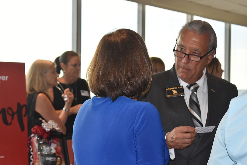 Andrew Vac reads a business card from Sandy Brabeck.