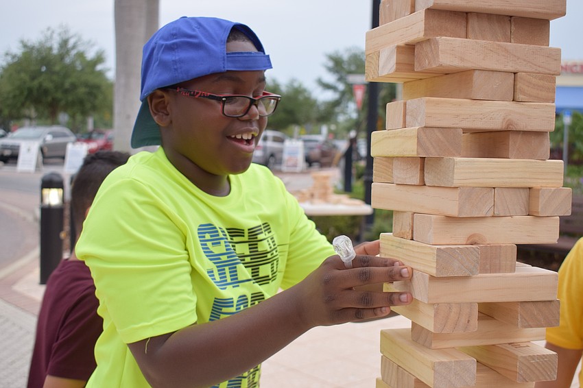 Parrish resident Darian Campbell, 9, carefully removes a block from the Jenga tower.