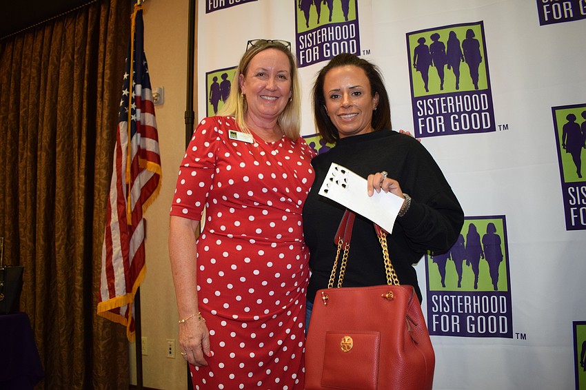 Sisterhood for Good's Kathy Fraley presents a designer purse to Lakewood Ranch's Valerie Demino after she won the second game of Bingo.