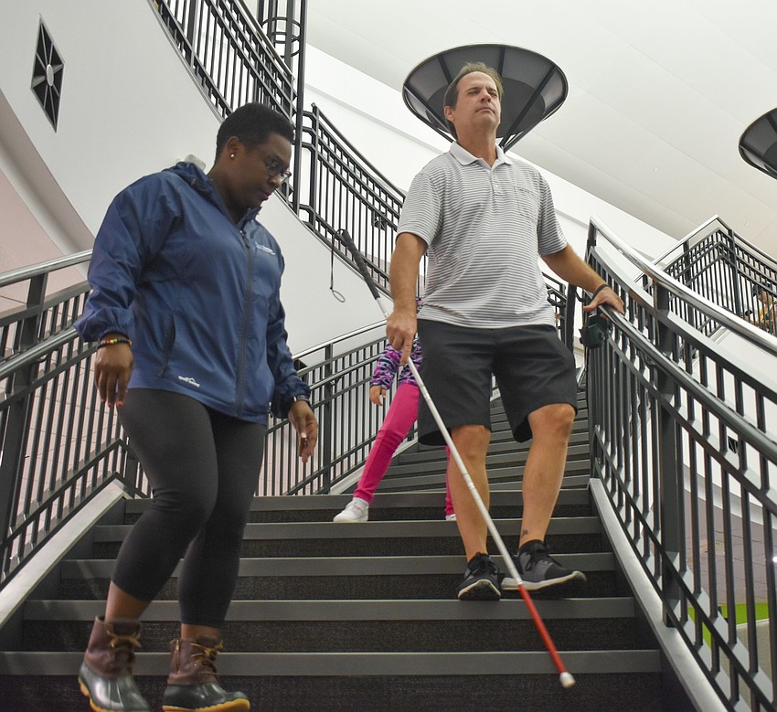 Latricia Gambrell talks Martin Rometsch through how to walk down stairs with a white cane.