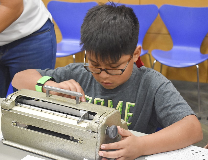 Cesar Barrios uses a braille machine to write a letter.