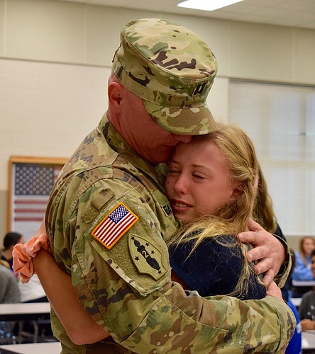 Seventh grader Marisa Easto cries as she hugs her dad, Capt. Josh Easto, who surprised her at school during lunch. Photo by Liz Ramos.