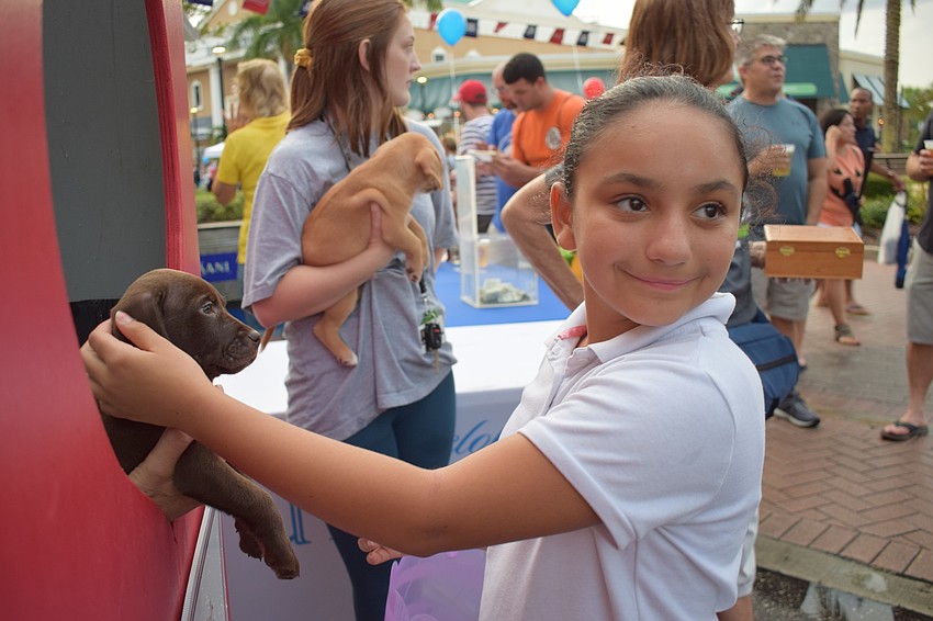 Bradenton resident Janiah Rodriguez, 8, pets a puppy at Nate's Honor Animal Rescue's smooch a pooch booth.