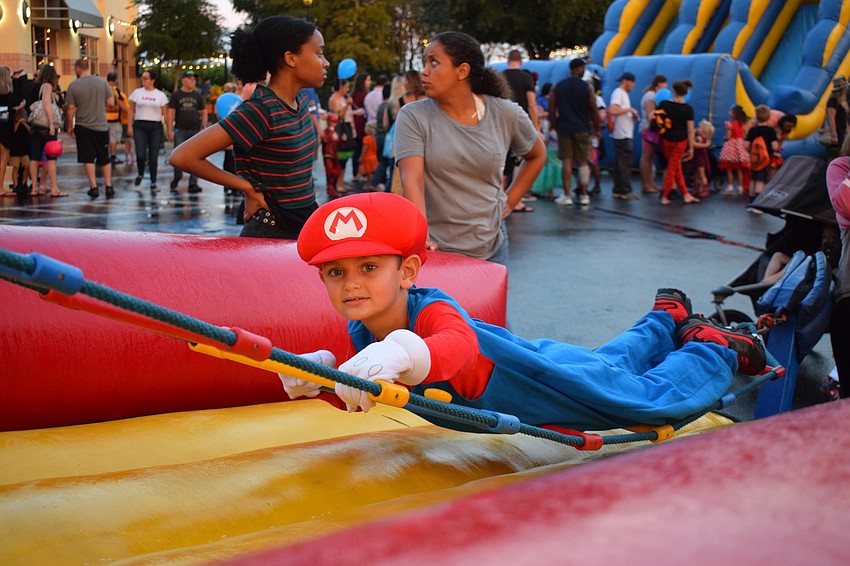Lakewood Ranch's Aiden Storey, 6, attempts to balance himself while climbing a ladder in the kids' zone at Boo Fest.