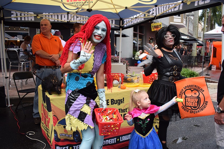 Jessica Linares and Miriam Ortiz, both with Truly Nolen, give candy to Sarasota's Chandler Swain, 3. Linares is Sally from 