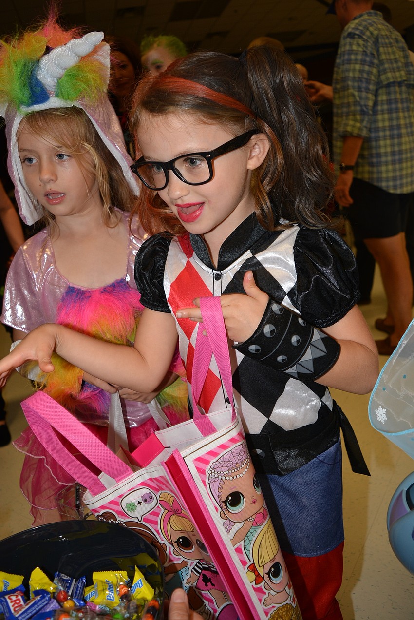 Six-year-old Shelby Kimbrell collects candy with her friend, Scarlett Hafner, behind