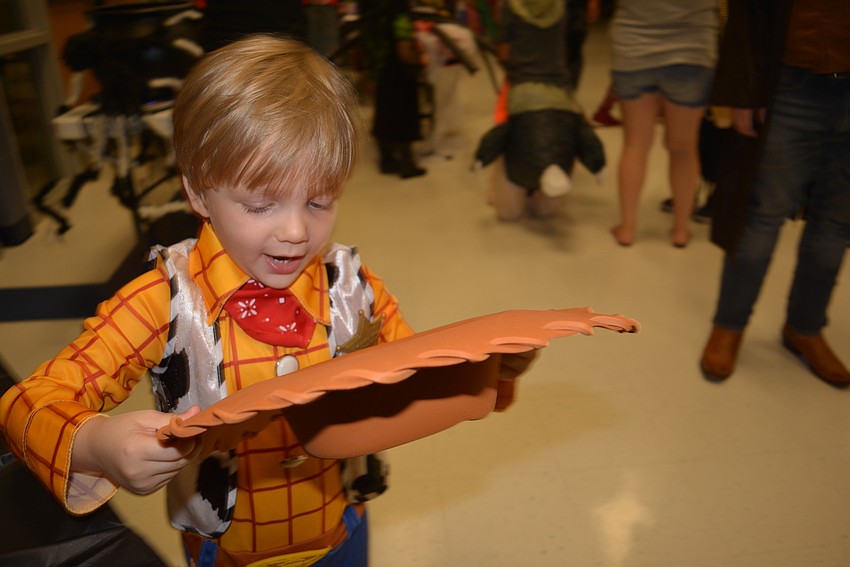 Preschooler Chris Dirden uses his hat to fetch candy and then dumps it into his bucket.