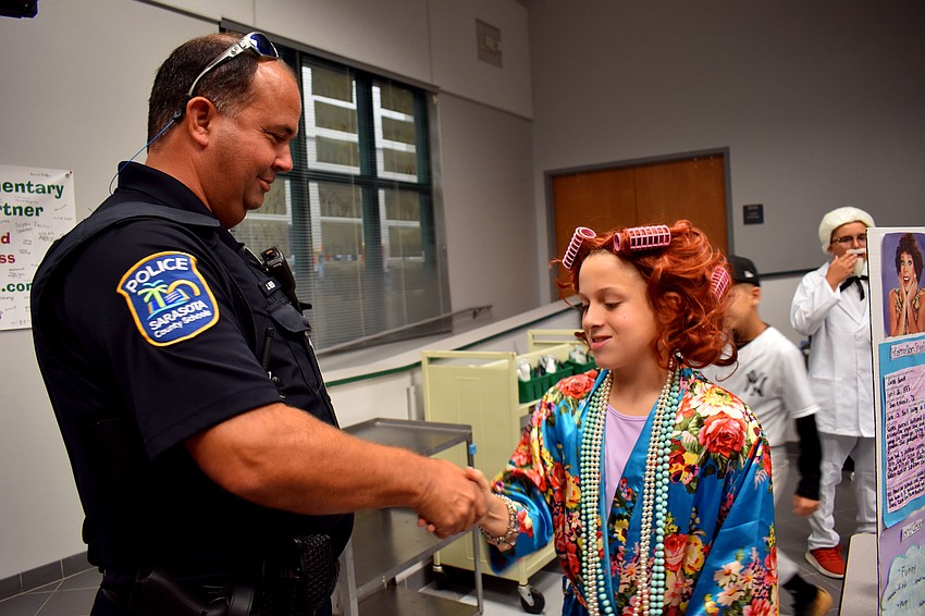 Officer Joe Reed does a secret handshake with Kyle Sirois who was dressed like Carol Burnett during Venice Elementary's wax museum event.