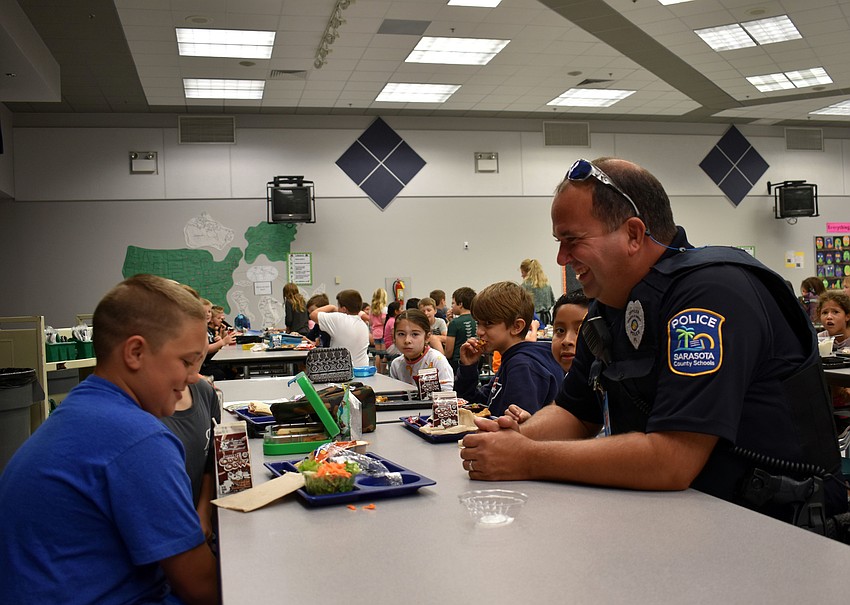 Officer Joe Reed sits down with students while they eat lunch.