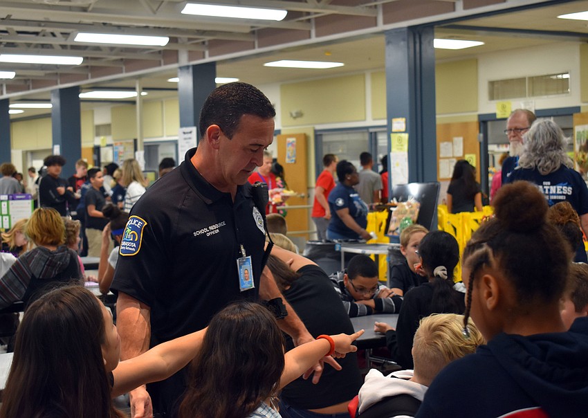 Officer Anthony Limite talks to McIntosh Middle School students during lunch.