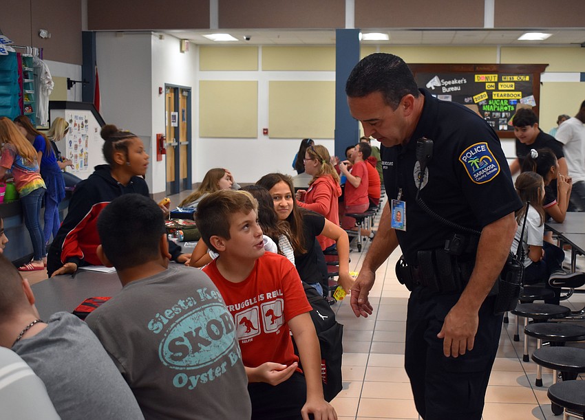 Officer Anthony Limite bends down to talk to sixth grade student Josh Flavell.