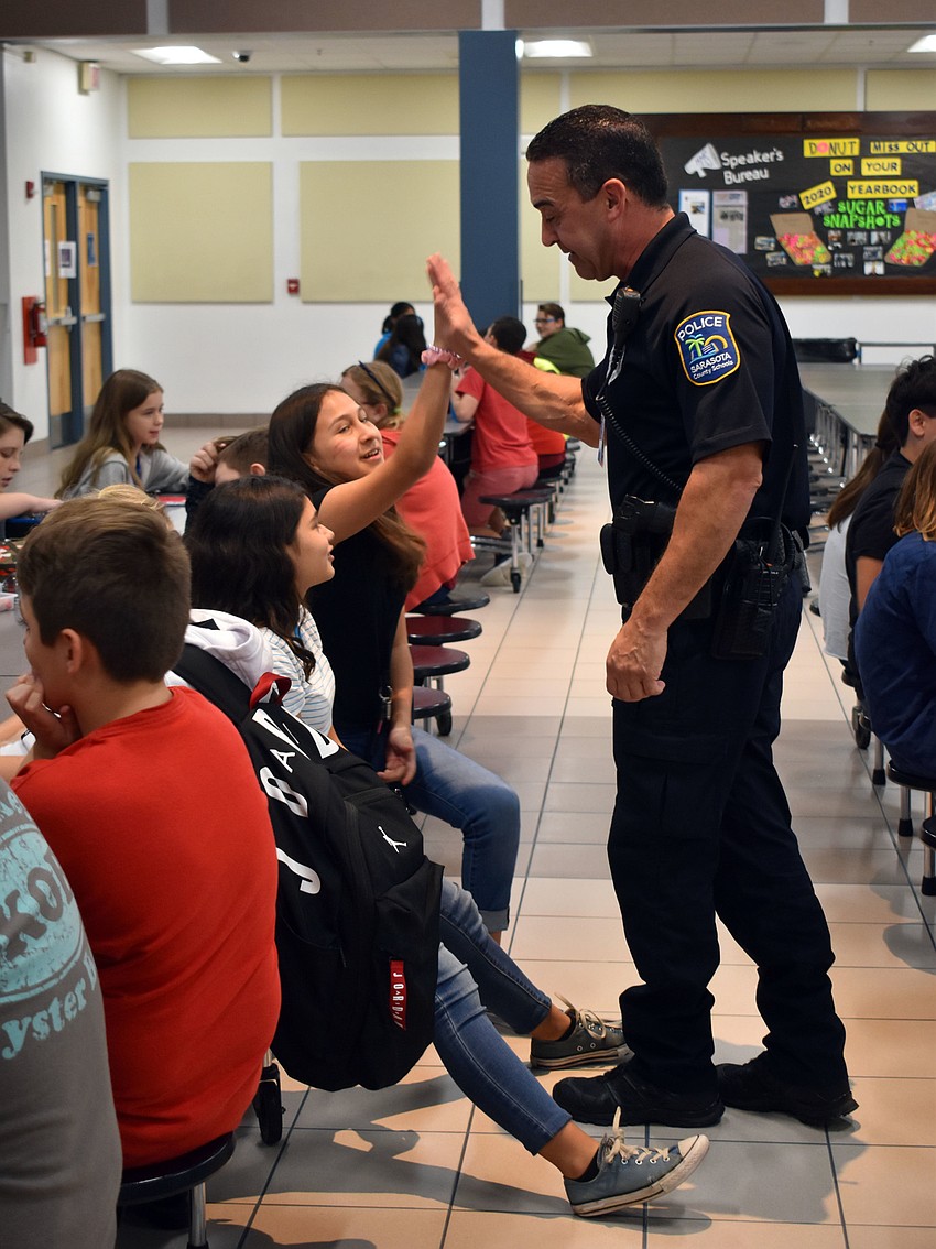 McIntosh Middle School sixth grade student Leilene Castro high  fives Officer Anthony Limite.