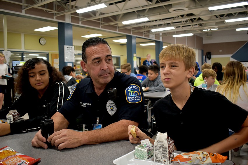 Whisper Farrior and Zack Renner talk with Officer Anthony Limite during lunch.