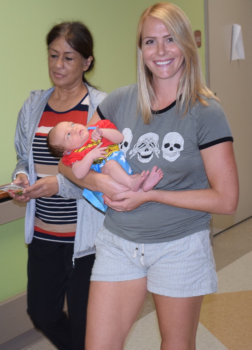 Wonder Woman Palmer Schmitz is carried by her mom, Palmetto's Laura Van Handel, during the parade. Laura said it was pain and happiness Oct. 2 when her daughter was born.