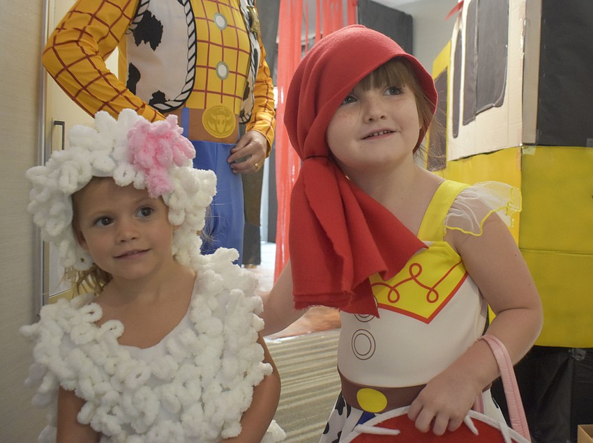Ava Cox, 3, and Taylor Evans, 4, peak around the corner as they see the trick-or-treaters coming.