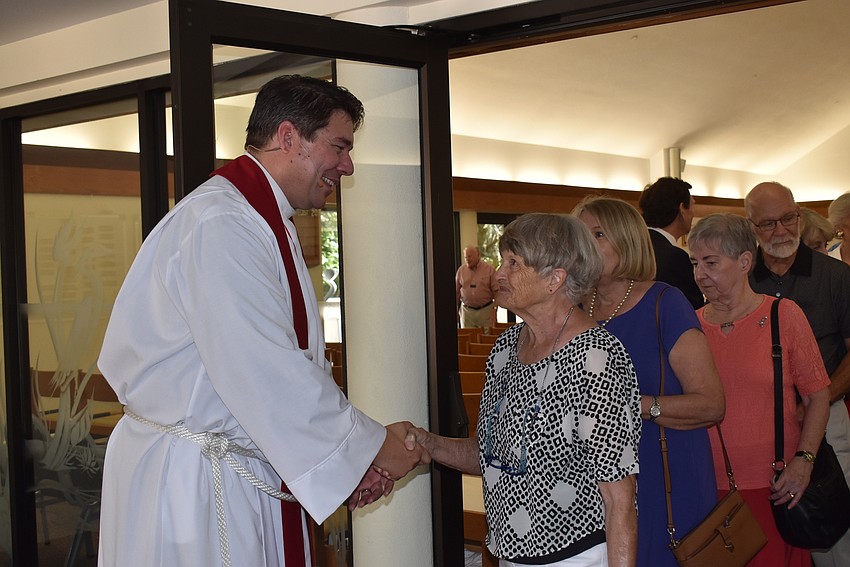Father Dave Marshall shakes hands with his congregants as they congratulate his new position.