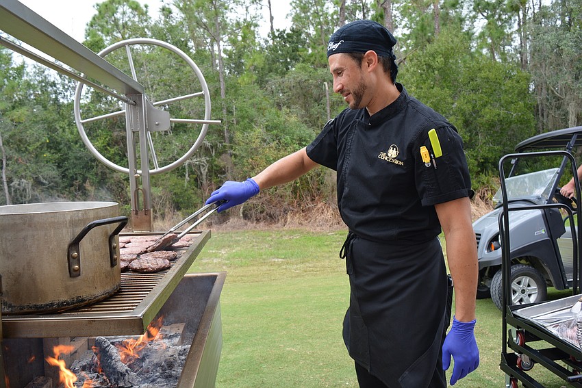Chef Washington Torres grills hamburgers over an open flame before the ribbon-cutting ceremony.