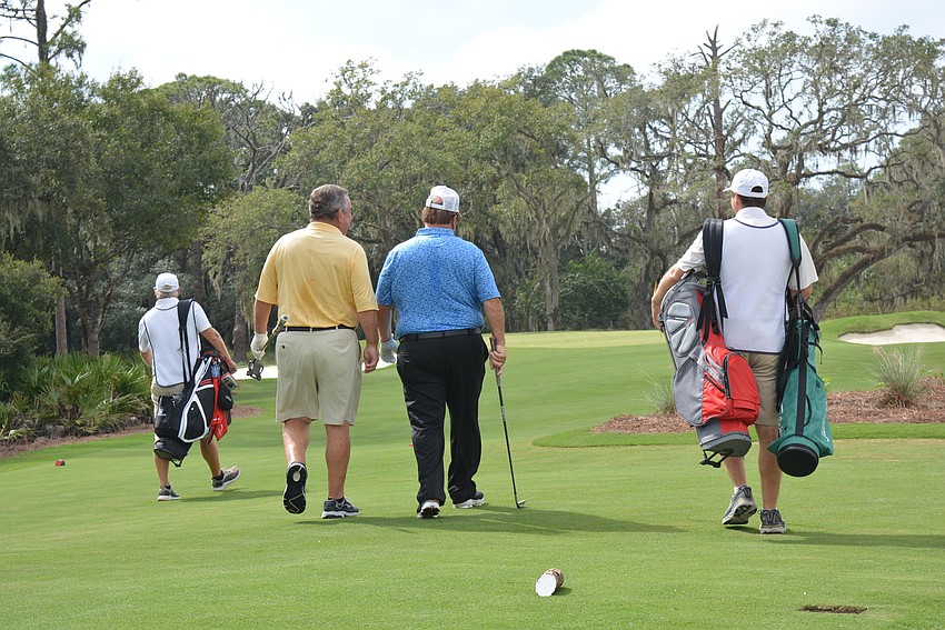 Golfer Tony Jacklin and Concession Golf Club owner Bruce Cassidy, center, walk to their balls at the first hole.